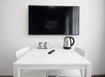 a white table with chairs and a tv on a wall at Alveo Suites in Prague