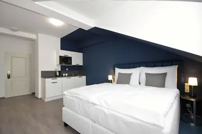 a bedroom with a large white bed and a blue wall at Alveo Suites in Prague