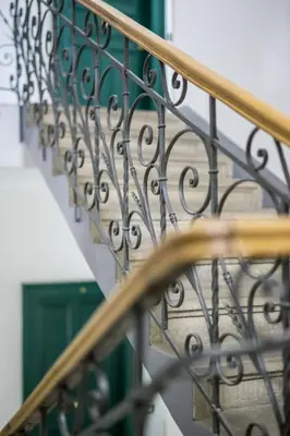 a metal railing on a staircase with a green door at Duskova Apartments in Prague