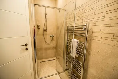 a bathroom with a shower with a glass door at Bourgeois Apartment in Cultural Heritage Building by Ruterra in Prague