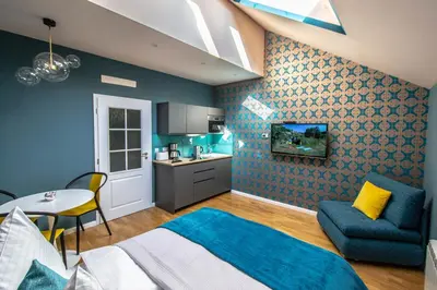 a bedroom with a bed and a table and a kitchen at Bourgeois Apartment in Cultural Heritage Building by Ruterra in Prague