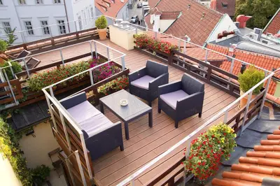 an outdoor deck with chairs and tables and flowers at Agnes - Apartments in Prague
