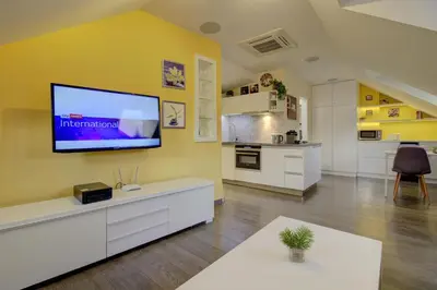 a living room with a flat screen tv on a yellow wall at Agnes - Apartments in Prague