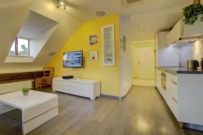 a kitchen with yellow walls and white cabinets and a table at Agnes - Apartments in Prague