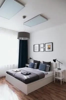 a white bedroom with a large bed with blue pillows at Apartment Gesse Jirsikova in Prague