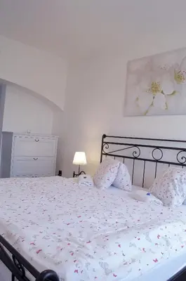 a white bedroom with a bed with flowers on it at Apartmány V Podzámčí II. in Mělník