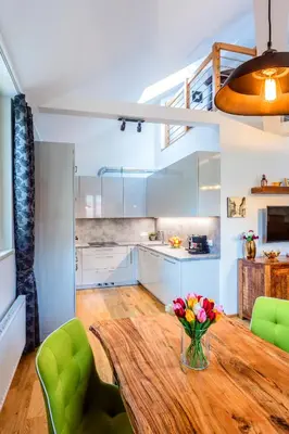 a kitchen with a wooden table and green chairs at Baranova Apartments in Prague