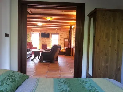 a bedroom with a bed and a chair and a living room at Ubytování Steak-Hredle in Hředle
