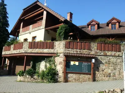 a building with a stone wall and wooden balcony at Ubytování Steak-Hredle in Hředle