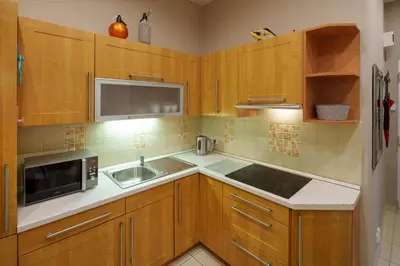 a kitchen with wooden cabinets and a sink and a microwave at Dlouhá Apartment with balcony in Prague