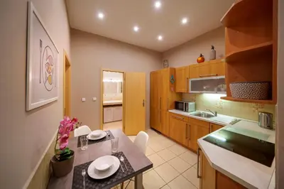 a kitchen with wooden cabinets and a table with chairs at Dlouhá Apartment with balcony in Prague