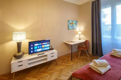 a bedroom with a television on a dresser with a desk at Dlouhá Apartment with balcony in Prague