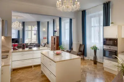a large kitchen with white cabinets and a table at Smetanovo nábřeží - Riverview Old Town Apartment in Prague