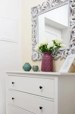a white dresser with a mirror and a vase with flowers at Bear Fountain Residence in Prague