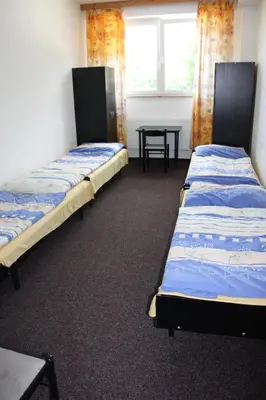 two beds in a room with a table and a window at Sporthotel BK Pod Lipou in Roudnice nad Labem