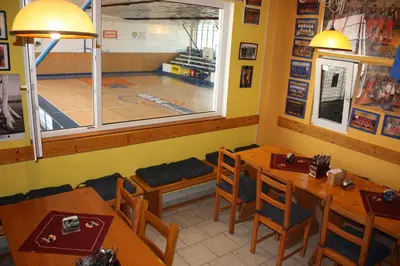 a dining room with wooden tables and a basketball court at Sporthotel BK Pod Lipou in Roudnice nad Labem