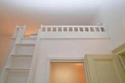 a loft bed in a room with a ladder at Lovely little cosy Apt in Prague in Prague