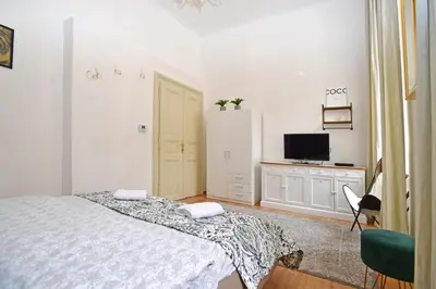 a white bedroom with a bed and a tv at Lovely little cosy Apt in Prague in Prague