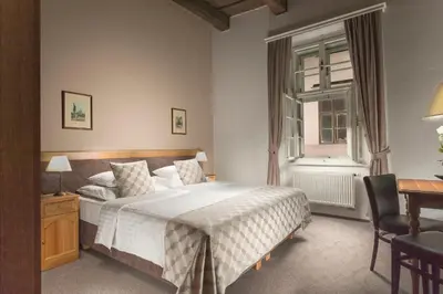 a bedroom with a bed and a desk and a window at Hotel Pod Věží in Prague