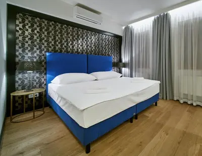 a bed in a room with a blue headboard at Antik Hotel Prague in Prague