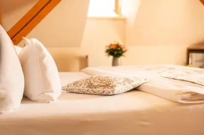 a white bed with pillows and a vase of flowers at Hotel Golden Key Prague Castle in Prague