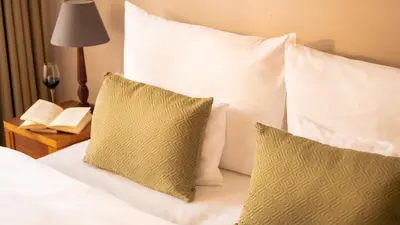 a bed with white pillows and a table with a lamp at Hotel Golden Key Prague Castle in Prague