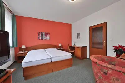 a bedroom with a bed and a tv and a couch at Attic Hotel in Prague