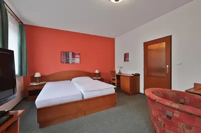 a bedroom with a bed and a tv and a couch at Attic Hotel in Prague