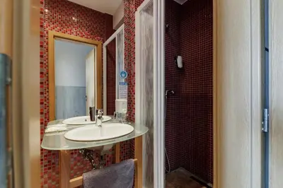 a bathroom with a sink and a red tiled wall at Royal Court Hotel in Prague