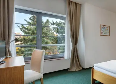 a bedroom with a window and a desk and a chair at Hotel Oya in Prague