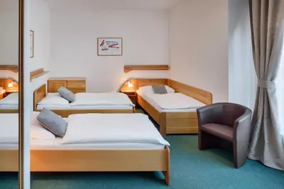 a room with three beds and a chair at Hotel Oya in Prague