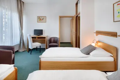 a hotel room with two beds and a desk at Hotel Oya in Prague