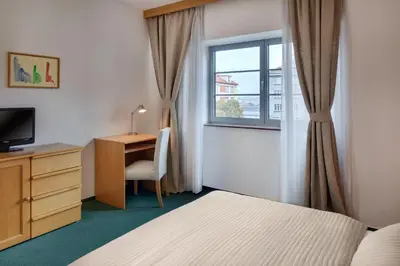 a bedroom with a bed and a desk and a window at Hotel Oya in Prague