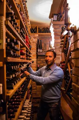 a man holding a bottle of wine in a wine cellar at Boat Hotel Matylda in Prague