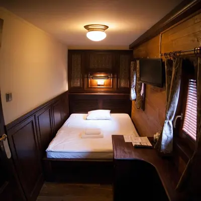 a small bedroom with a bed and a desk at Boat Hotel Matylda in Prague