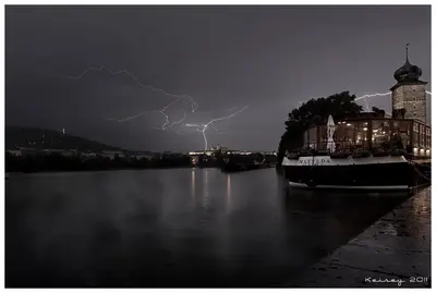a lightning storm over a body of water with a boat at Boat Hotel Matylda in Prague