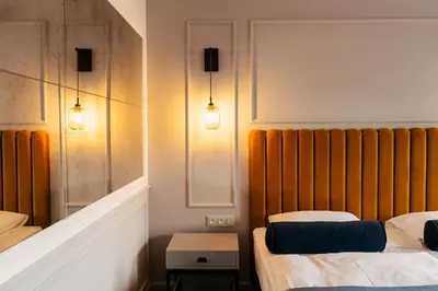 two beds in a room with two lights on the wall at The Hotel Fitzgerald in Prague