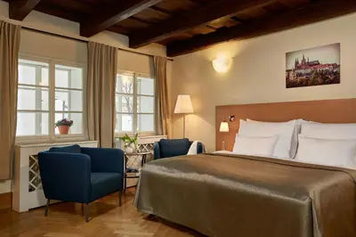 a hotel room with a bed and two chairs at Mostecká 12 Residence in Prague