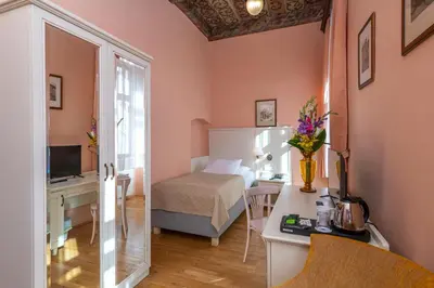 a small room with a bed and a desk with a table at Hotel Cerny Slon in Prague