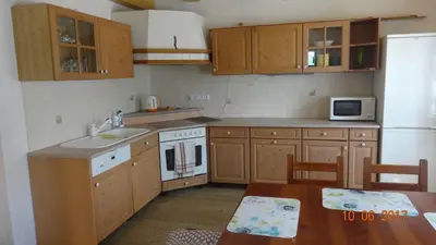 a kitchen with wooden cabinets and a sink and a table at Chaloupka za potůčkem in Županovice