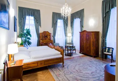 a living room with a bed and a chandelier at Château Liblice in Byšice