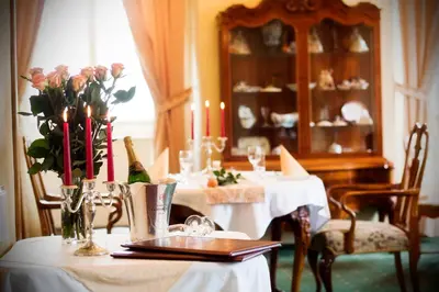 a dining room with two tables with flowers and candles at Château Liblice in Byšice
