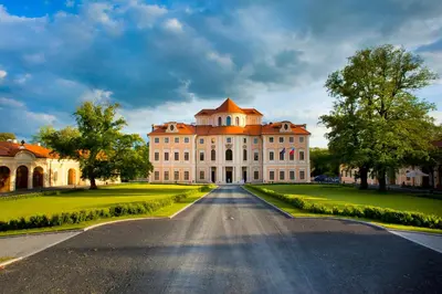 a large white building with a red roof on a road at Château Liblice in Byšice