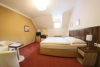 a hotel room with a large bed and a chair at Hotel Koruna in Karlštejn