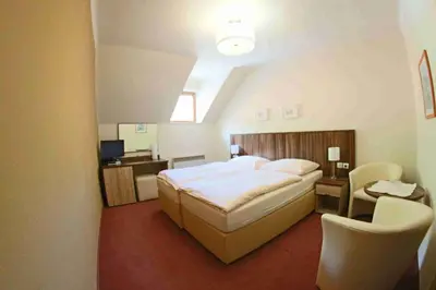 a bedroom with a bed and a desk and chairs at Hotel Koruna in Karlštejn