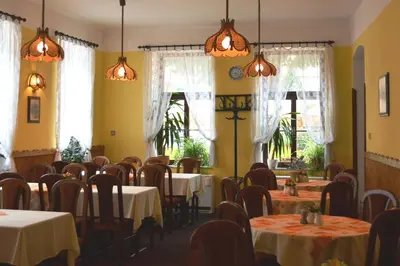 a dining room with tables and chairs and windows at Hotel Koruna in Karlštejn