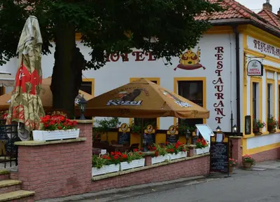 a restaurant with an umbrella in front of a building at Hotel Koruna in Karlštejn