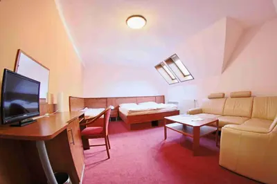 a living room with a couch and a table with a television at Hotel Koruna in Karlštejn