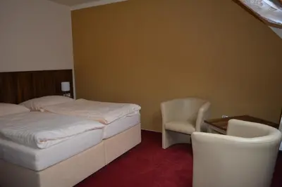a bedroom with a bed and a desk and a chair at Hotel Koruna in Karlštejn