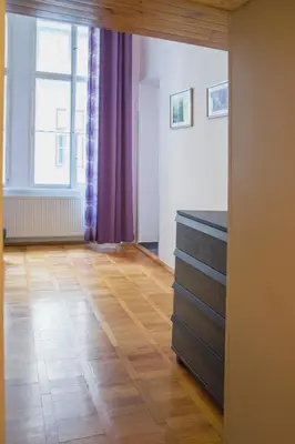 a room with a wooden floor and a dresser and a window at Apartment Jindrisska 25 in Prague
